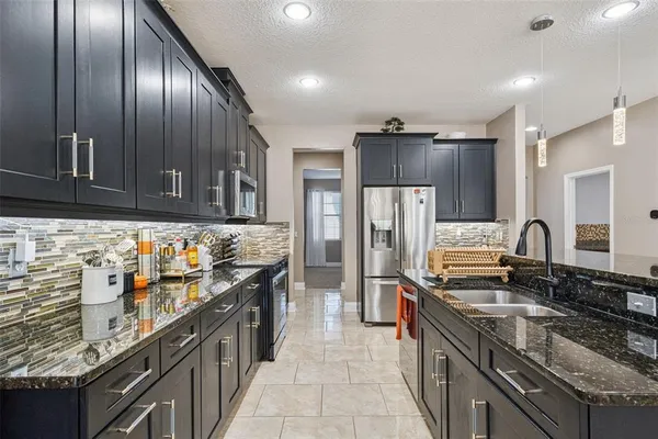 a kitchen with stainless steel appliances kitchen island granite countertop a stove top oven a sink dishwasher a dining table and chairs with wooden floor
