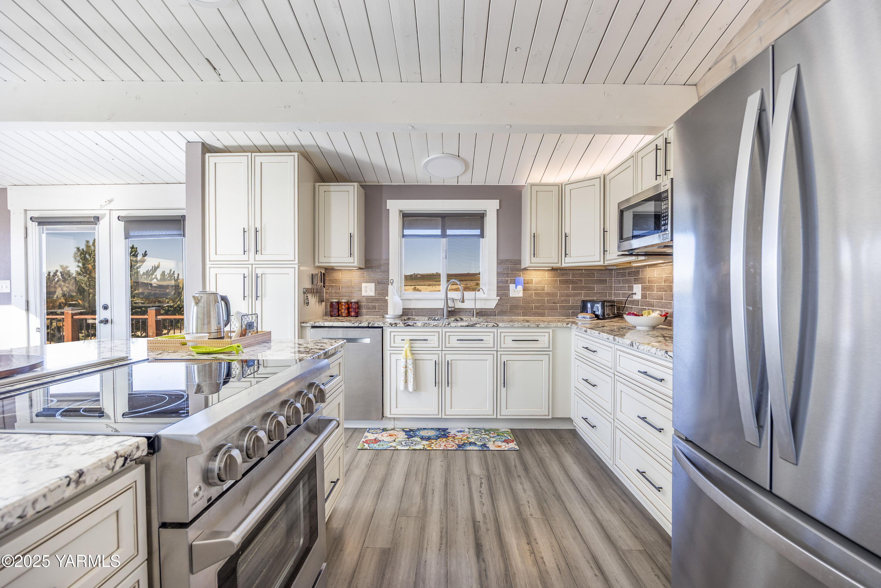 22207 West Gerrick Road Benton City, WA 99320 - Photo 27 of 60 a kitchen with a sink dishwasher a stove and white cabinets with wooden floor