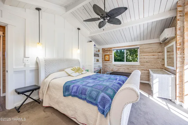 a bedroom with a large bed a flat tv screen and a dresser