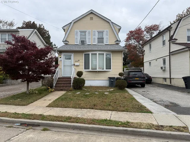 a view of a white house with large windows next to a road