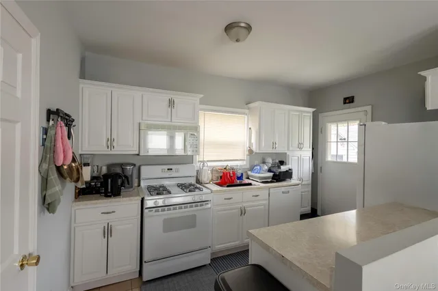 a kitchen with a sink dishwasher stove and white cabinets