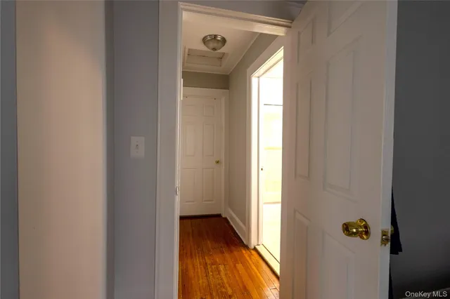 a view of a hallway with wooden floor and a bathroom