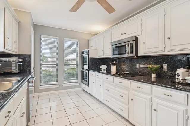 a kitchen with granite countertop a stove top oven a sink a counter space and cabinets