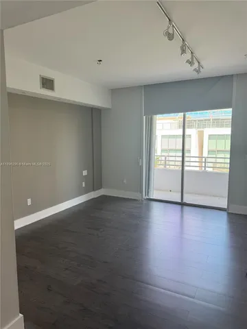 an empty room with wooden floor and windows with curtains