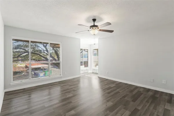 a view of an empty room with a window and wooden floor