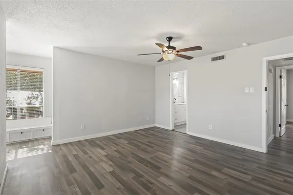 an empty room with wooden floor and windows