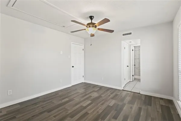 an empty room with wooden floor ceiling fan and windows