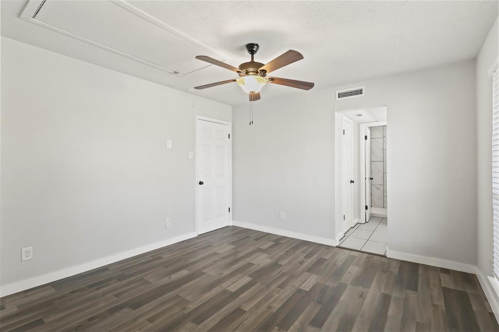 10526 Stone Canyon Road, Unit 201 Dallas, TX 75230 - Photo 16 of 28 an empty room with wooden floor ceiling fan and windows
