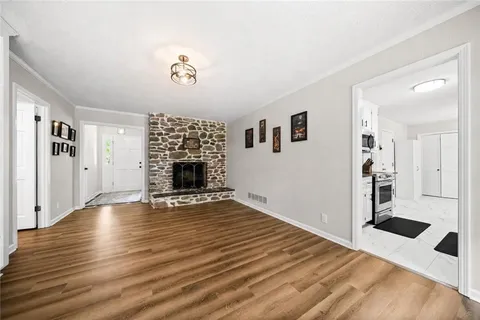 a view of empty room with wooden floor and kitchen view