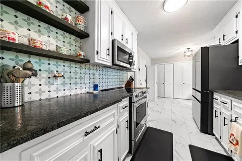 a kitchen with stainless steel appliances granite countertop a stove a sink and a microwave