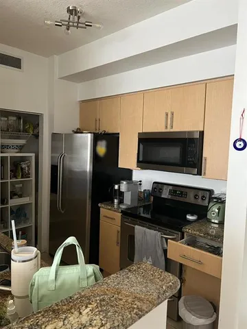 a kitchen with stainless steel appliances kitchen island granite countertop a refrigerator and a stove top oven