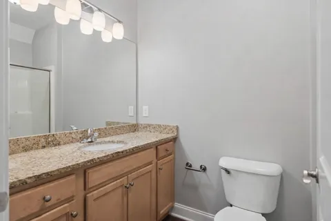 a bathroom with a granite countertop toilet sink and mirror