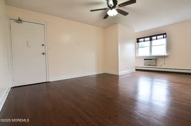 an empty room with wooden floor chandelier fan and windows