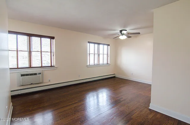 an empty room with wooden floor chandelier fan and windows