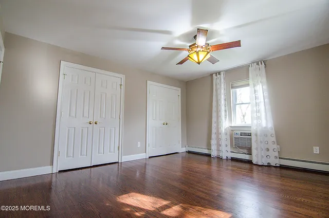 a view of an empty room with window and wooden floor