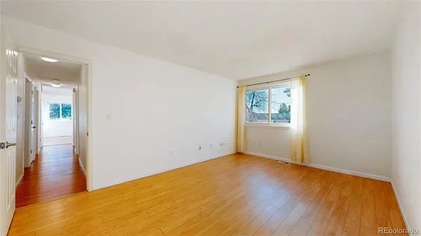 a view of an empty room with wooden floor and a window