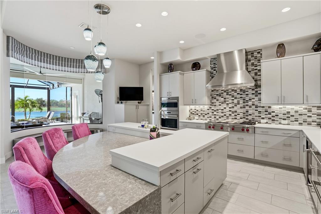 9177 Esplanade Boulevard Naples, FL 34119 - Photo 19 of 50 Kitchen featuring a center island, wall chimney range hood, decorative backsplash, recessed lighting, and hanging light fixtures