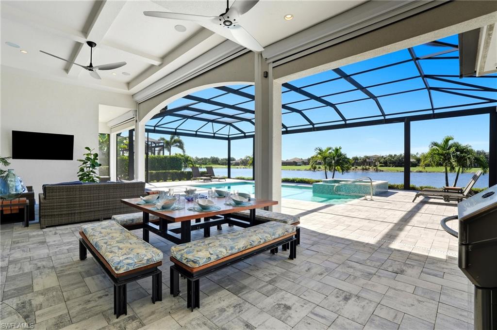 9177 Esplanade Boulevard Naples, FL 34119 - Photo 38 of 50 View of patio with a sunroom, a ceiling fan, a lanai, a pool with connected hot tub, and a water view