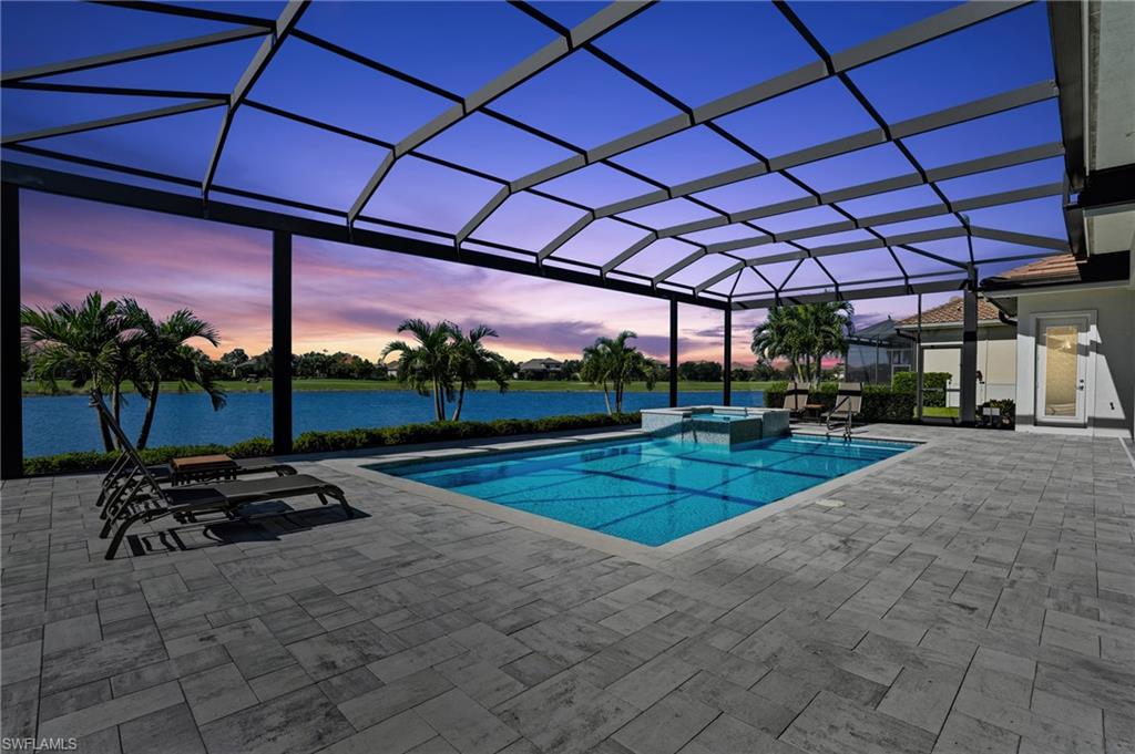 9177 Esplanade Boulevard Naples, FL 34119 - Photo 41 of 50 Pool at dusk featuring glass enclosure, a patio area, a sunroom, and a pool with connected hot tub
