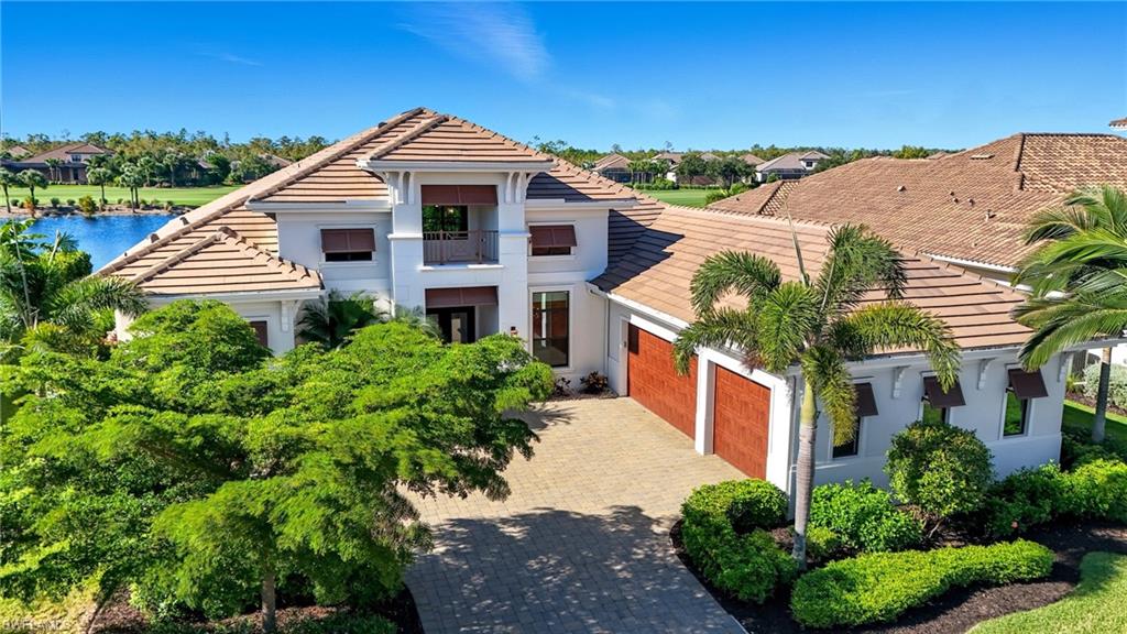 9177 Esplanade Boulevard Naples, FL 34119 - Photo 47 of 50 View of front facade featuring a tile roof, stucco siding, driveway, a balcony, and a water view