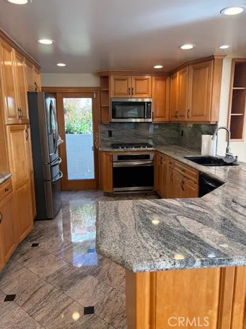 a kitchen with stainless steel appliances granite countertop a refrigerator a stove top oven a sink and dishwasher