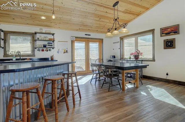 a dining room with wooden floor a chandelier a wooden table and chairs