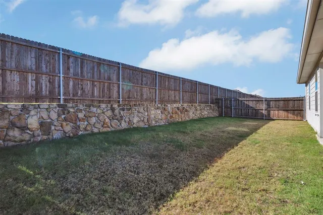 a view of backyard with wooden fence