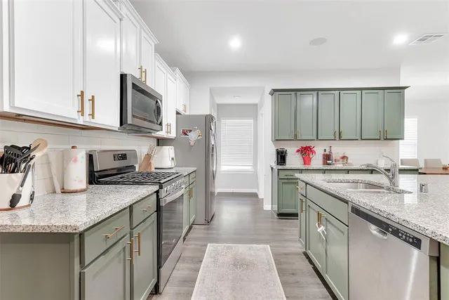 a kitchen with stainless steel appliances granite countertop a sink stove refrigerator and cabinets