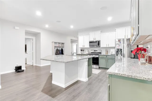 a kitchen with stainless steel appliances granite countertop a sink dishwasher a refrigerator and a stove with wooden floors