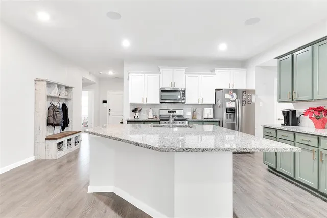 a large kitchen with granite countertop a sink a counter top space and stainless steel appliances