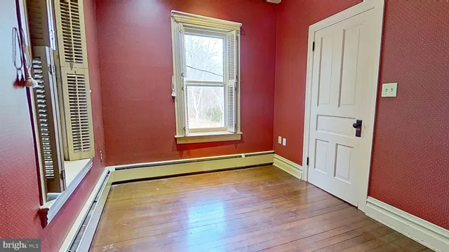 a view of an empty room with window and wooden floor
