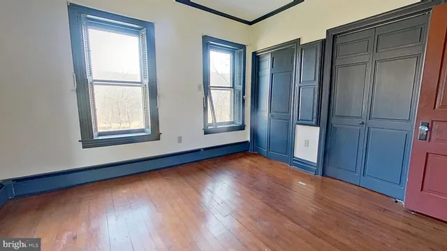 an empty room with wooden floor and windows