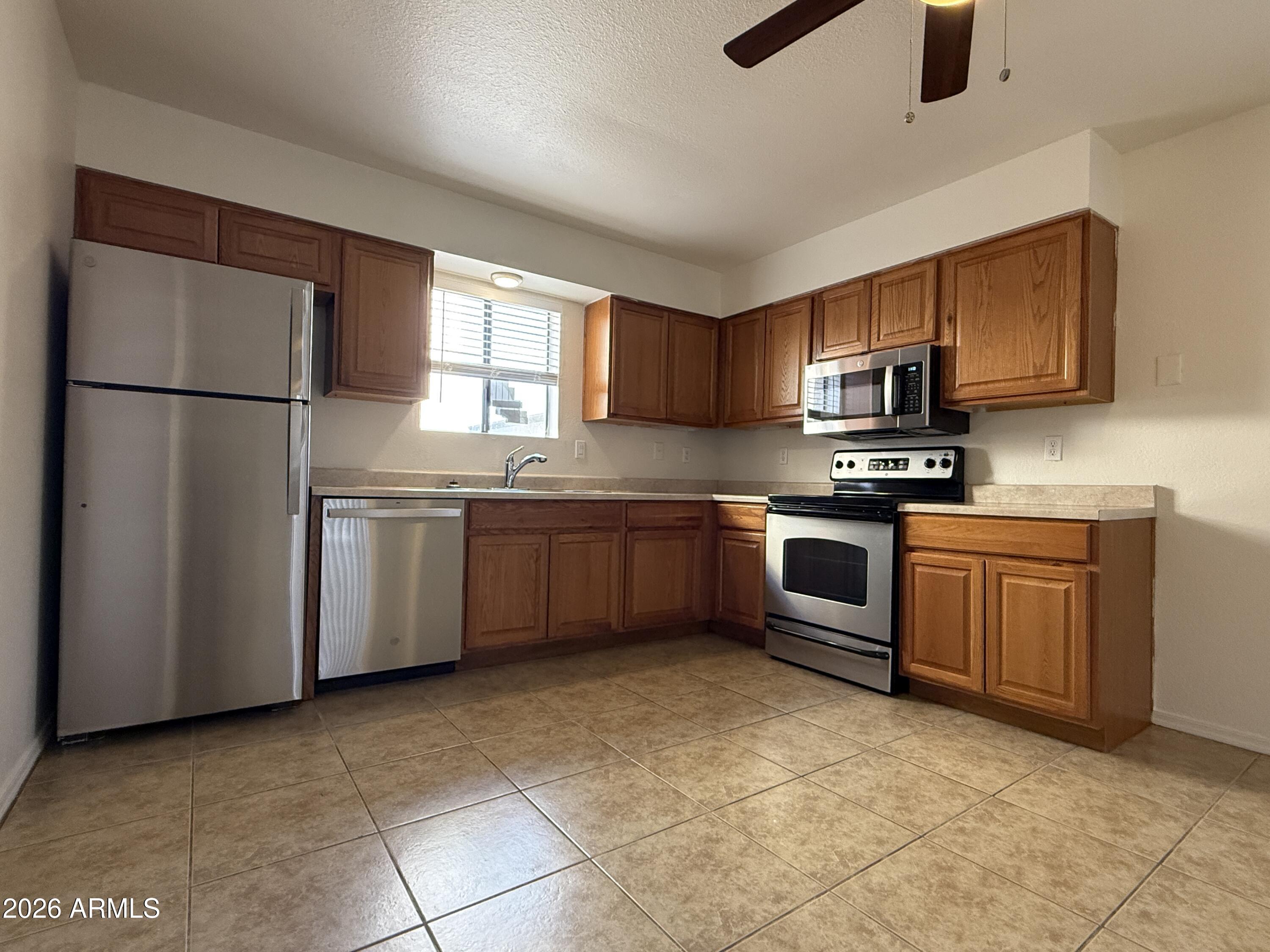 2650 East McKellips Road, Unit 105 Mesa, AZ 85213 - Photo 7 of 13 a kitchen with stainless steel appliances granite countertop a stove a sink dishwasher a refrigerator and a microwave oven