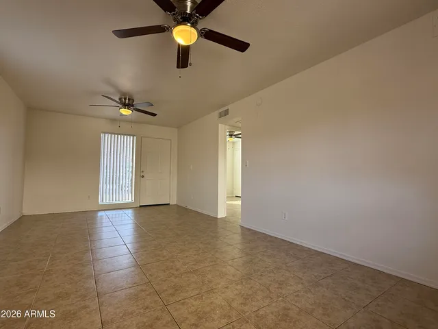 an empty room with windows and fan