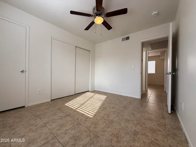 an empty room with closet and a chandelier fan