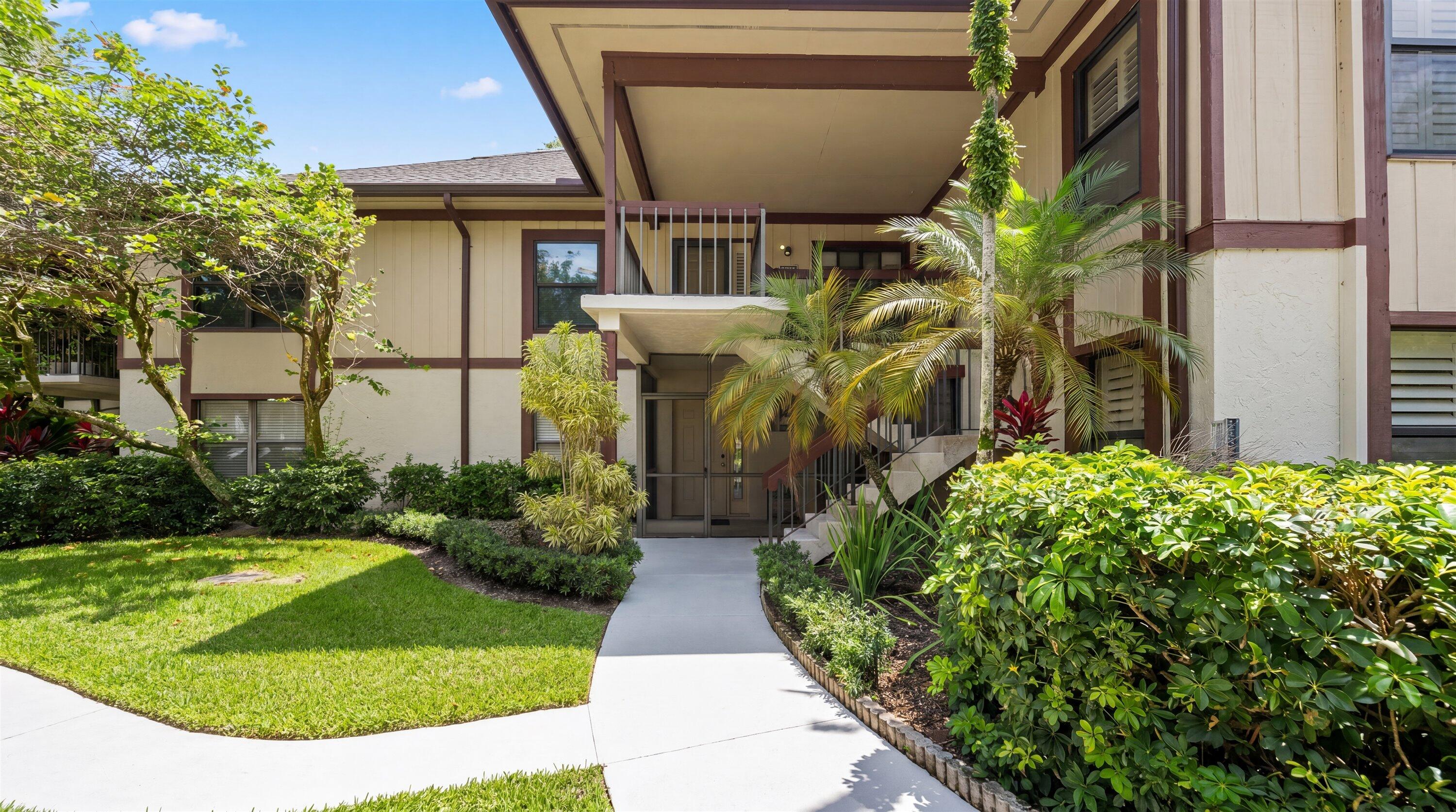 13400 Polo Road West, Unit 203 Wellington, FL 33414 - Photo 1 of 26 a view of a house with a small yard plants and large tree
