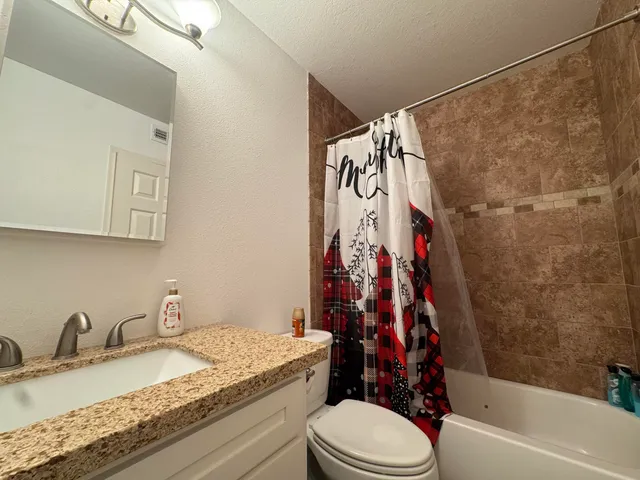 a bathroom with a granite countertop sink toilet and shower