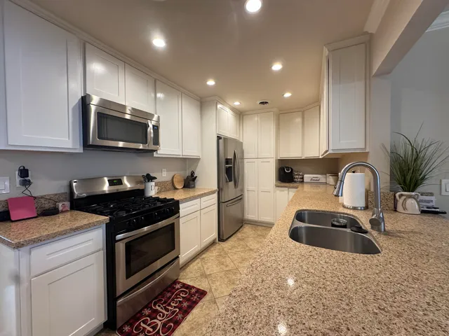 a kitchen with granite countertop a sink stainless steel appliances and cabinets