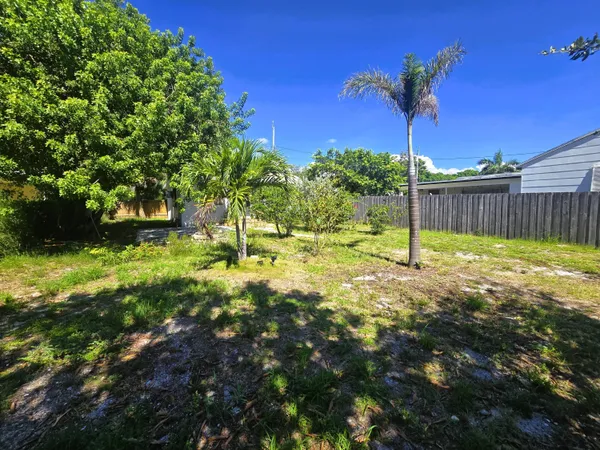 a view of yellow house with a yard and a large tree