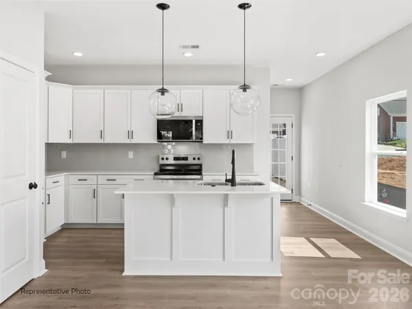 a kitchen with stainless steel appliances kitchen island granite countertop a sink a stove and a refrigerator