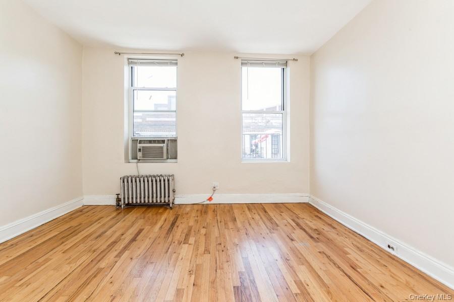 41-32 53rd Street Queens, NY 11377 - Photo 19 of 24 an empty room with wooden floor and windows