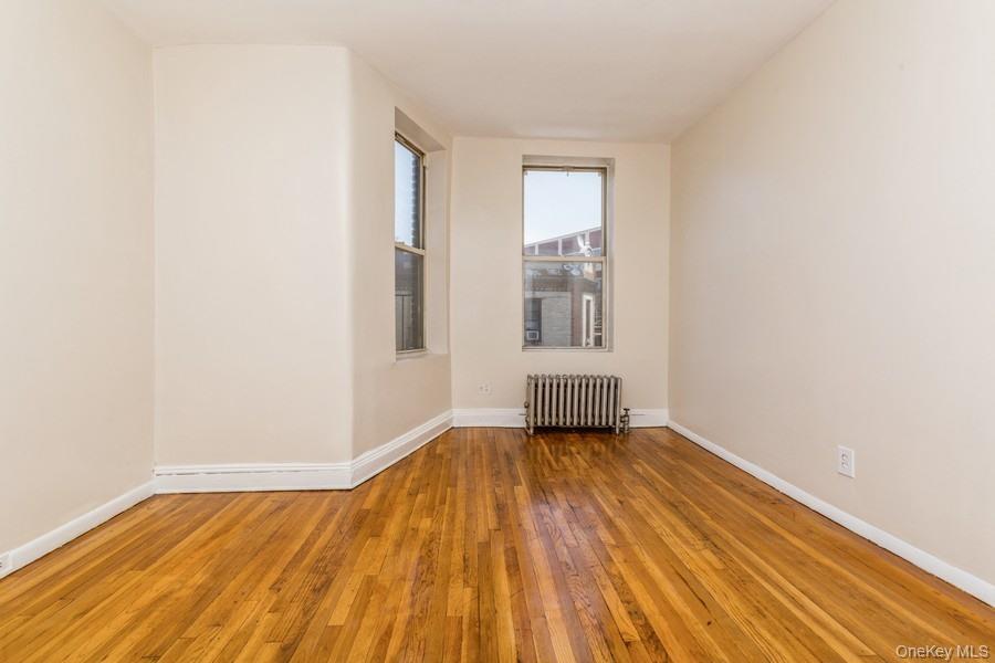 41-32 53rd Street Queens, NY 11377 - Photo 21 of 24 a view of an empty room with wooden floor and a window