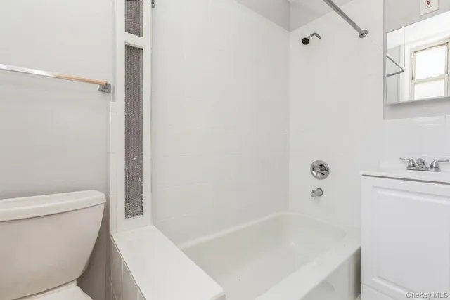 a white bath tub sitting next to a white toilet and vanity