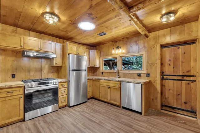 a kitchen with stainless steel appliances granite countertop a refrigerator a stove and a wooden floors