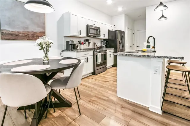 a kitchen with stainless steel appliances kitchen island granite countertop a table chairs and a refrigerator