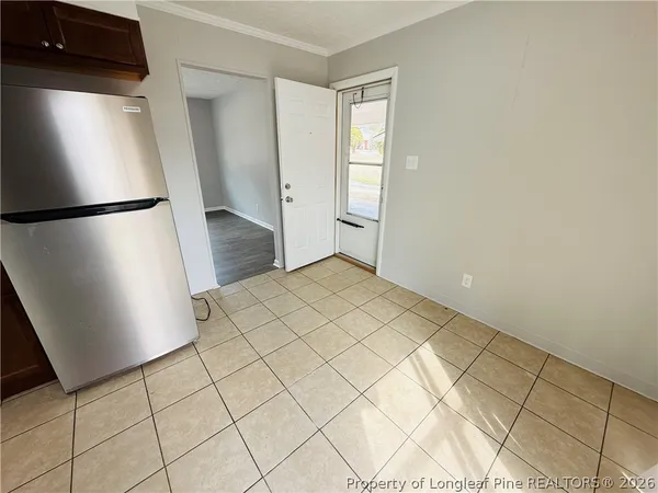 a view of a refrigerator in kitchen and an empty room