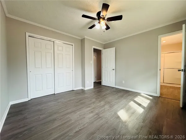 a view of empty room with wooden floor and fan
