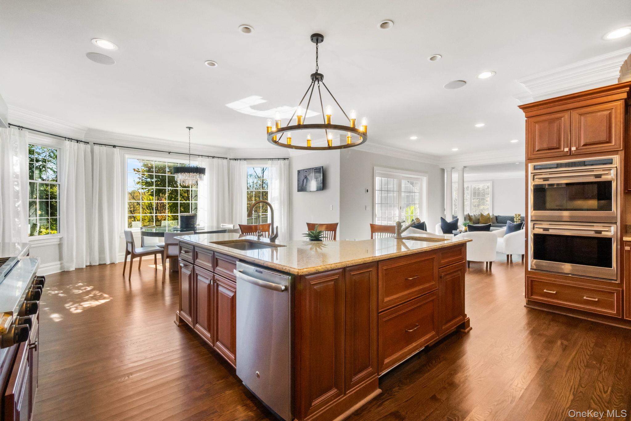 496 Long Ridge Road Bedford, NY 10576 - Photo 13 of 49 Kitchen featuring brown cabinets, ornamental molding, light stone countertops, a chandelier, and stainless steel appliances