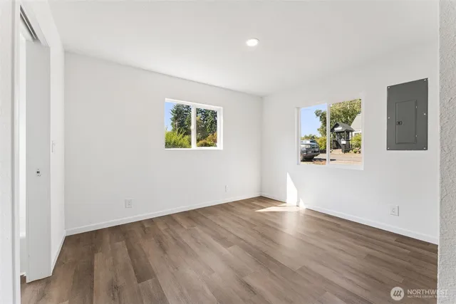 an empty room with wooden floor and windows