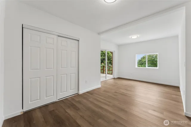 an empty room with wooden floor a ceiling fan and windows